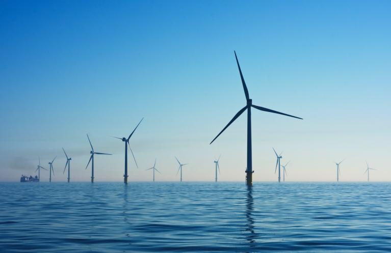 A photograph of several wind turbines, standing in the ocean. Image by Nicholas Doherty.